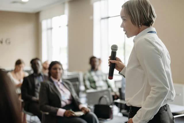 A presenter holding a microphone during a professional speaking session