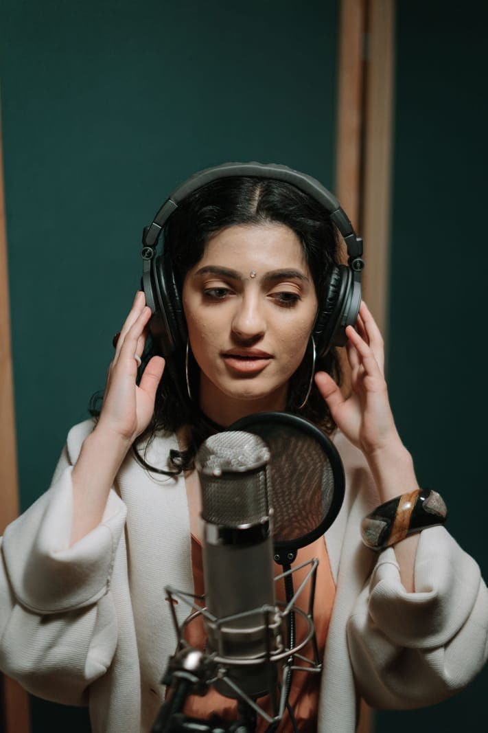 A woman wearing headphones at a studio microphone